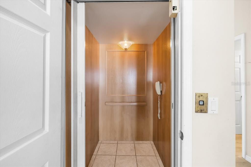 An elevator interior features wood-paneled walls, a tiled floor, and a mounted telephone — 4295 NEWPORT DRIVE, HERNANDO BEACH, FL