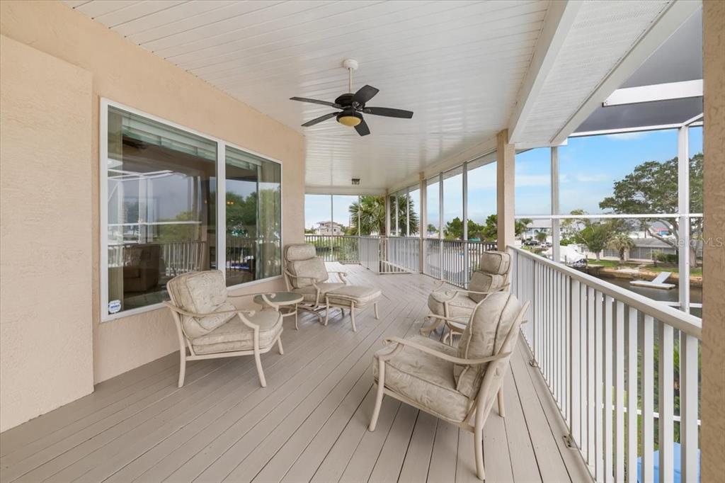 A covered, screened-in balcony features light-colored patio furniture and a ceiling fan overlooking a canal — 4295 NEWPORT DRIVE, HERNANDO BEACH, FL