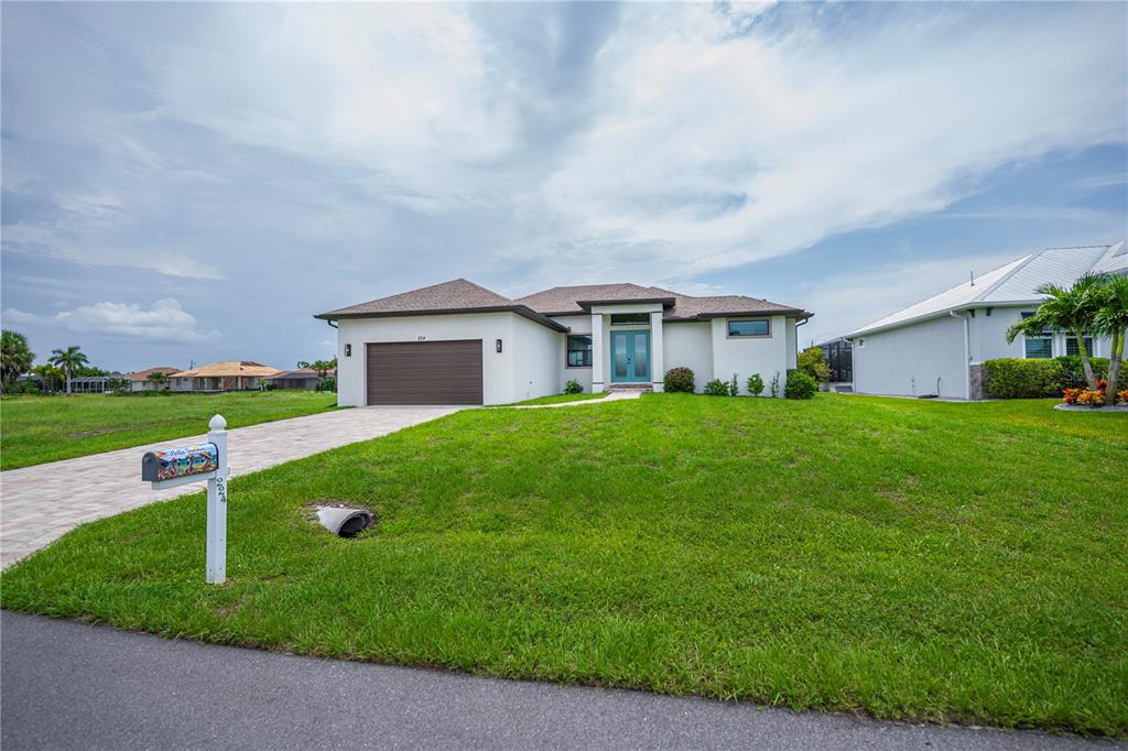 A single-story house with a brown garage door, teal front door, and a grassy lawn — 224 W PINE VALLEY LANE, ROTONDA WEST, FL