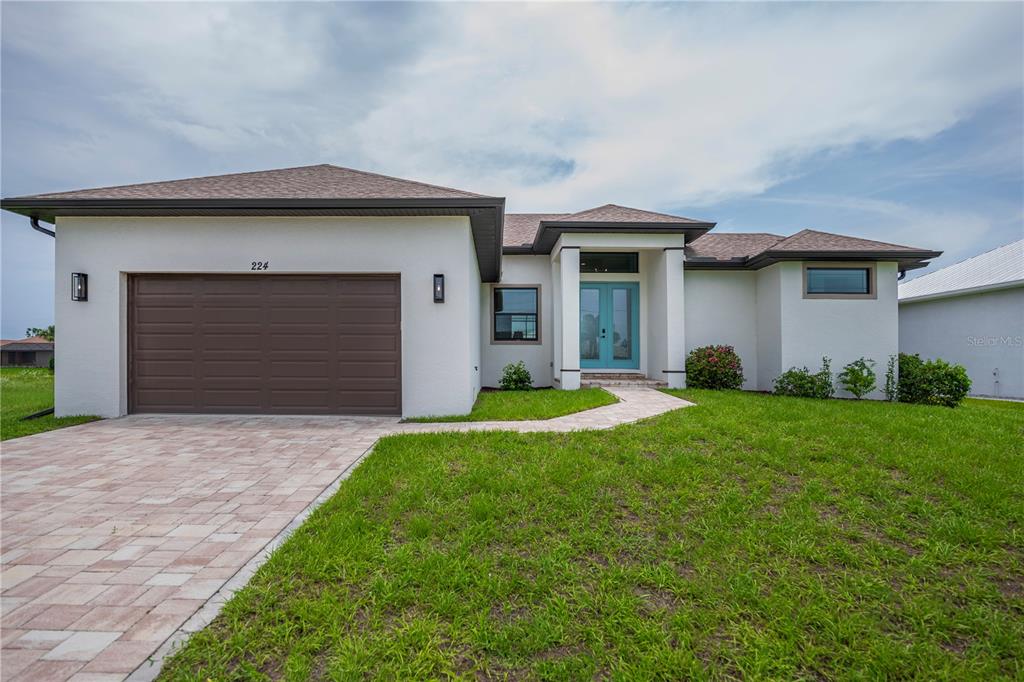 A single-story house with a white stucco exterior, a brown garage door, and a blue door — 224 W PINE VALLEY LANE, ROTONDA WEST, FL