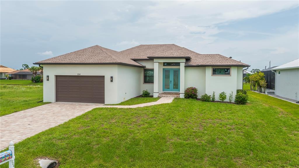 A single-story house with a light-colored stucco exterior, a two-car garage, and a turquoise door — 224 W PINE VALLEY LANE, ROTONDA WEST, FL