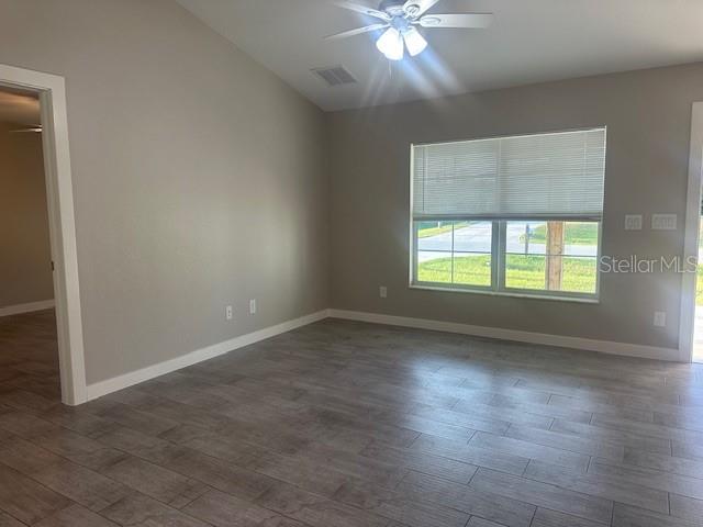 A living room features light gray walls, wood-look tile flooring, and a ceiling fan — 651 CHAMBER STREET NW, PORT CHARLOTTE, FL