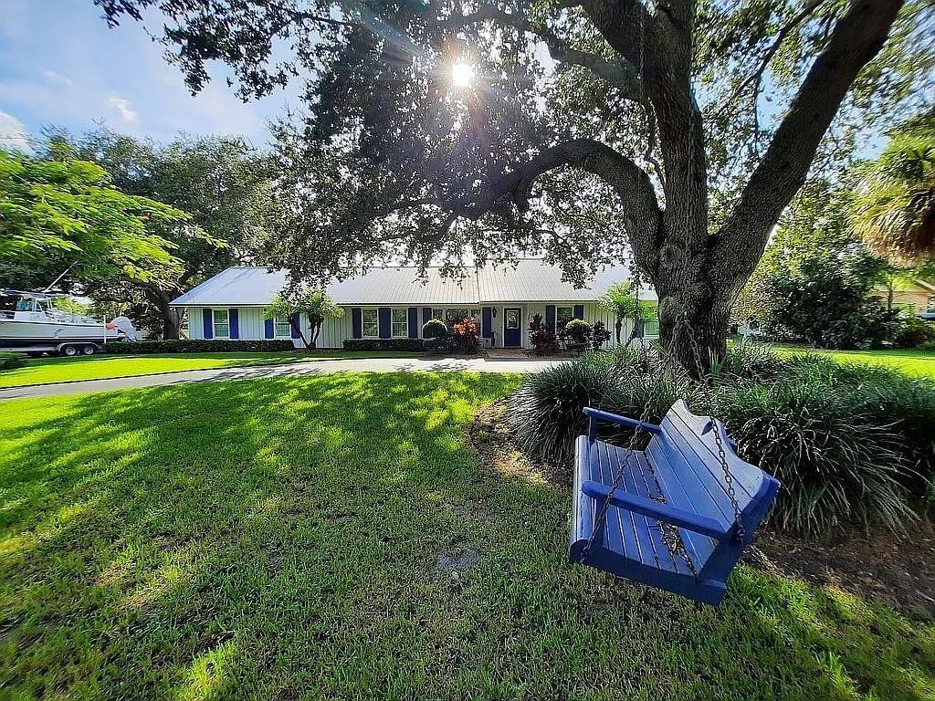 A blue wooden swing hangs from a large tree in front of a white house — 155 31st Avenue, Vero Beach FL 32968, VERO BEACH, FL