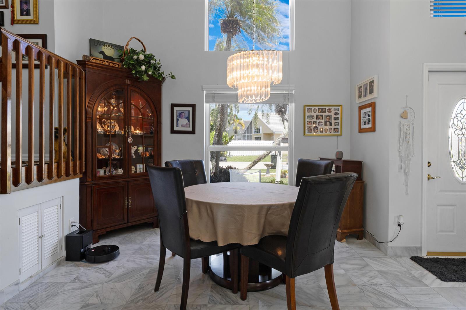 A dining area features a round table, dark chairs, a crystal chandelier, and marble flooring — 5525 NW 54th Circle, Coconut Creek FL 33073, COCONUT CREEK, FL