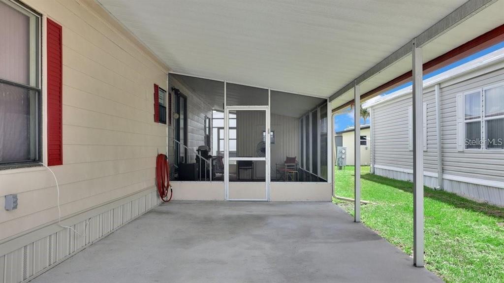 A covered concrete patio leads to a screened-in porch between two manufactured homes — 4212 CEDARWOOD STREET, WINTER HAVEN, FL