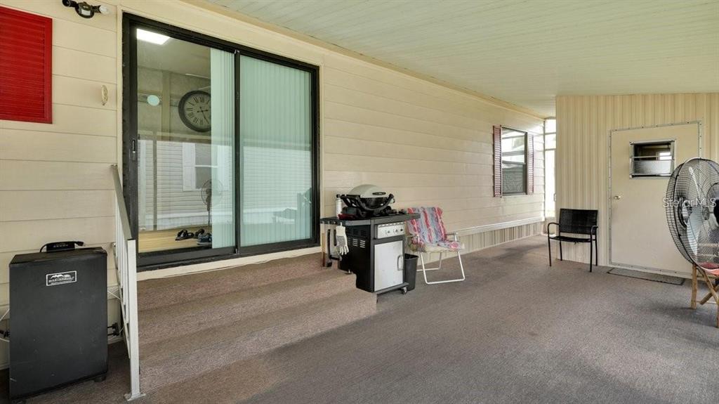 A covered patio features gray carpeting, a sliding glass door, a grill, and outdoor furniture — 4212 CEDARWOOD STREET, WINTER HAVEN, FL
