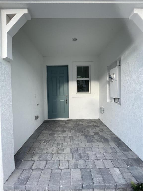 A covered entryway features gray paver flooring, a blue front door, and a white exterior — 615 Parsons Way, Deerfield Beach FL 33442, DEERFIELD BEACH, FL
