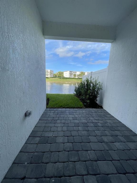 A covered patio with dark stone pavers overlooks a small grassy area and a lake — 615 Parsons Way, Deerfield Beach FL 33442, DEERFIELD BEACH, FL