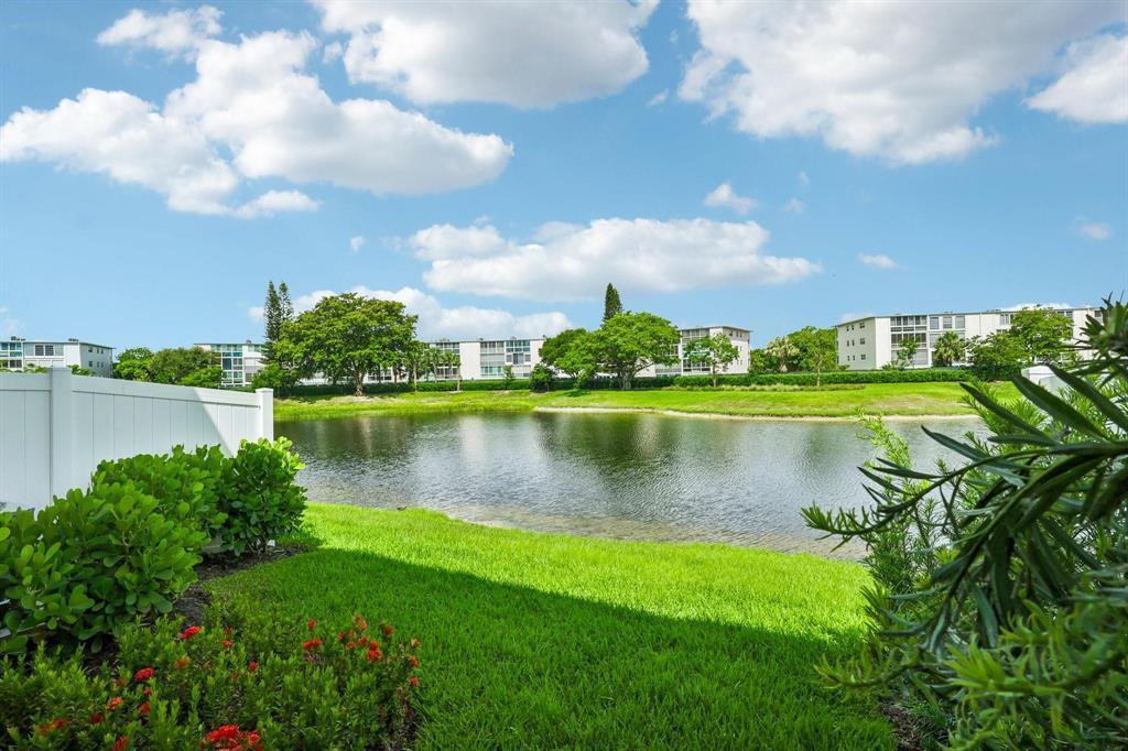 A grassy lawn overlooks a small lake with apartment buildings in the background — 615 Parsons Way, Deerfield Beach FL 33442, DEERFIELD BEACH, FL