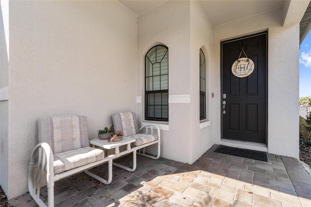 A paved front porch features two chairs, a small table, and a dark front door — 2639 STARGRASS CIRCLE, CLERMONT, FL