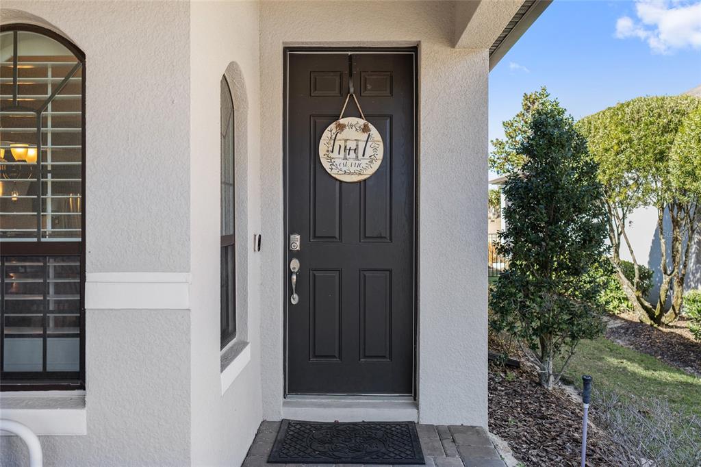 A dark front door with a decorative sign sits under a covered entryway — 2639 STARGRASS CIRCLE, CLERMONT, FL