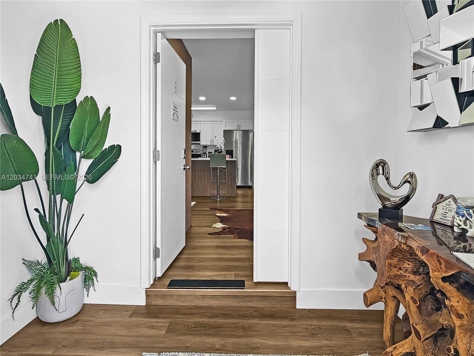 An entryway leads into a kitchen with wood flooring, white cabinets, and stainless steel appliances — 621 NW 59th Ave, Miami FL 33126, MIAMI, FL