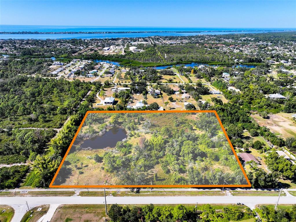 An aerial view shows a rectangular, wooded lot with a small pond outlined in orange — 370 N PINE STREET, ENGLEWOOD, FL