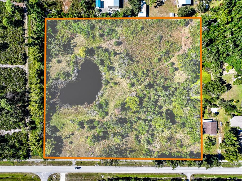 An aerial view shows a rectangular plot of land featuring a pond and scattered trees — 370 N PINE STREET, ENGLEWOOD, FL