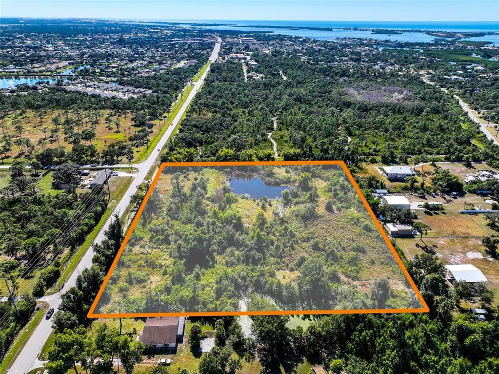 An aerial view shows a rectangular plot of land with a pond and vegetation — 370 N PINE STREET, ENGLEWOOD, FL
