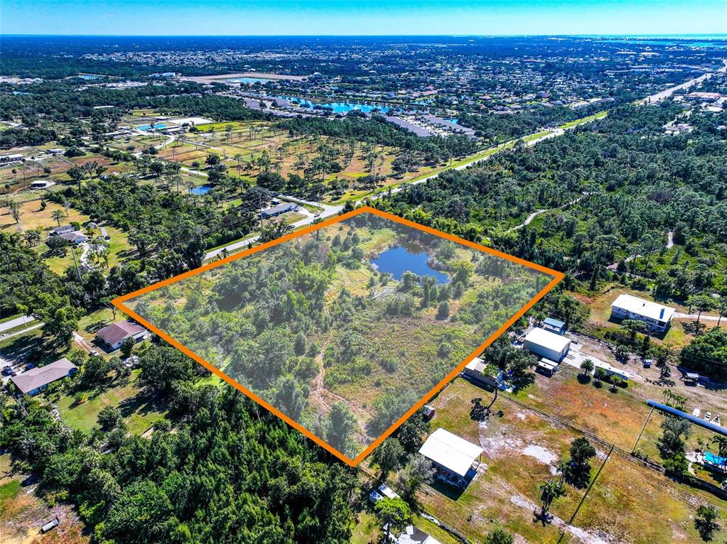 An aerial view shows a rectangular lot with a small pond and dense vegetation — 370 N PINE STREET, ENGLEWOOD, FL