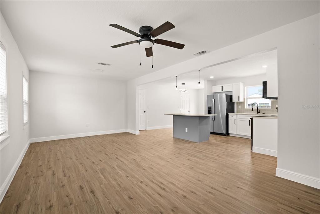 An open-concept living area features light wood-look flooring, a ceiling fan, and a modern kitchen — 6711 S GABRIELLE STREET, TAMPA, FL
