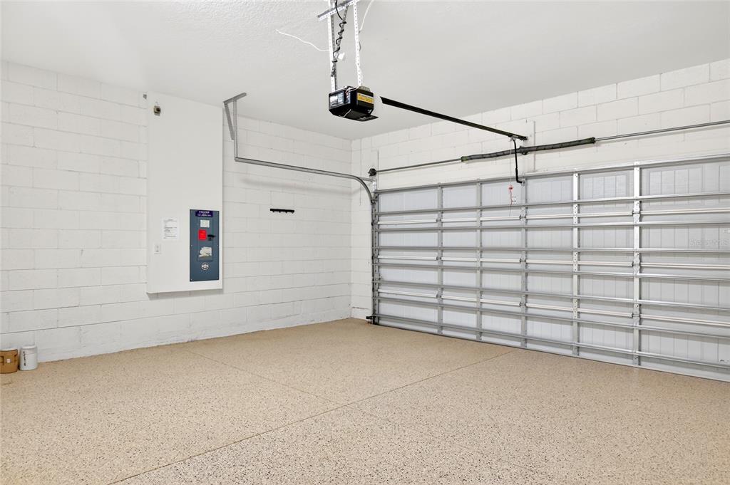 A garage with a speckled epoxy floor, white block walls, and a metal roll-up door — 9149 SW 62ND TERRACE ROAD, OCALA, FL