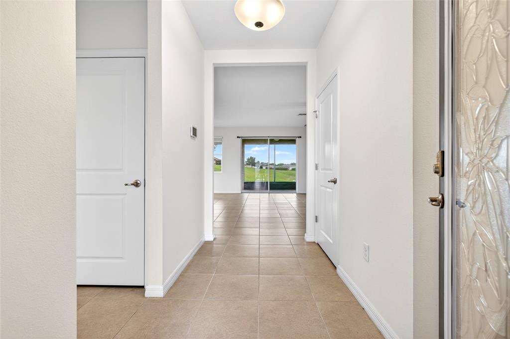 A tiled entryway leads to a hallway with white doors and a view of a backyard — 9149 SW 62ND TERRACE ROAD, OCALA, FL