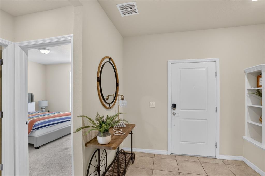 An entryway features a console table with a mirror, tile flooring, and a bedroom doorway — 7573 OAK SPRING LANE, DAVENPORT, FL