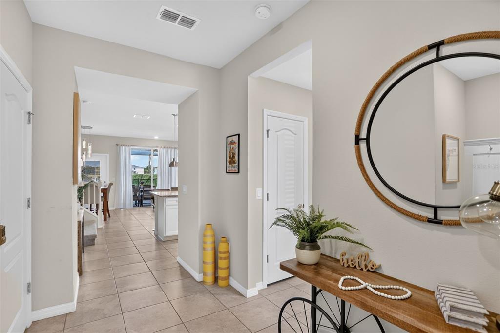 A tiled entryway features a console table with a mirror and a view into a kitchen — 7573 OAK SPRING LANE, DAVENPORT, FL