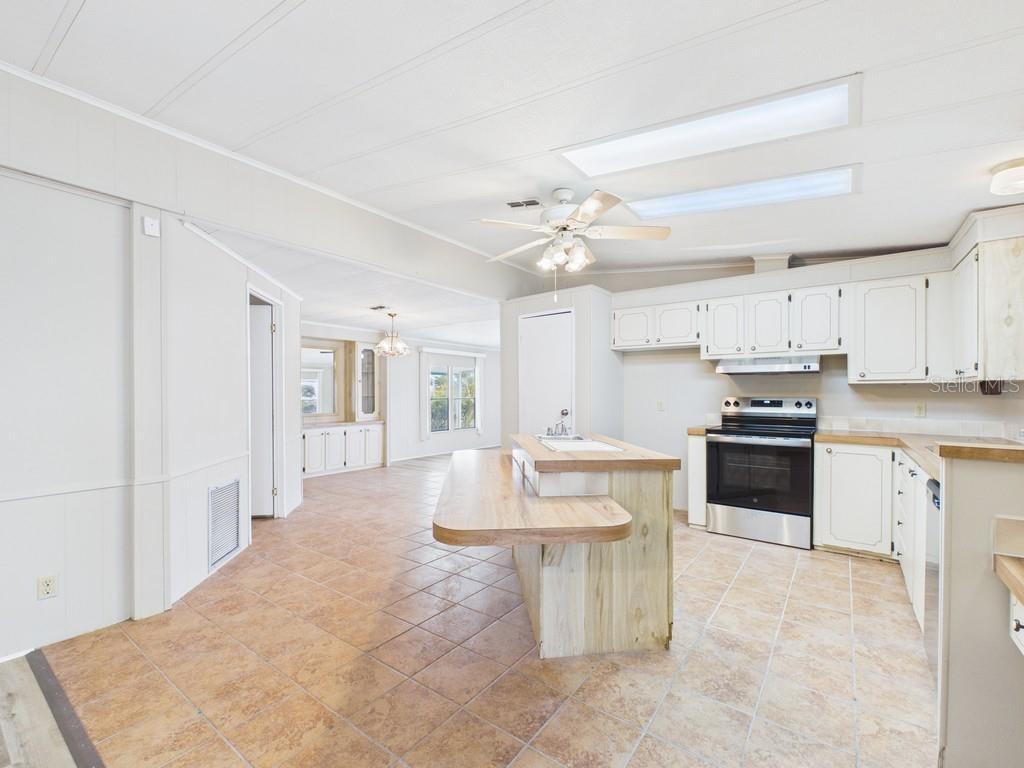A kitchen with tile floors, white cabinets, a wooden island, and an adjacent dining area — 9212 DENMARSH DRIVE, BROOKSVILLE, FL