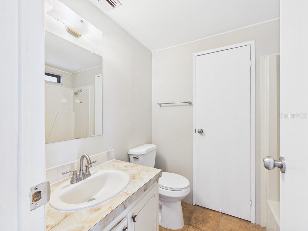 A bathroom features a marble-look vanity, a white toilet, and a mirror above the sink — 9212 DENMARSH DRIVE, BROOKSVILLE, FL