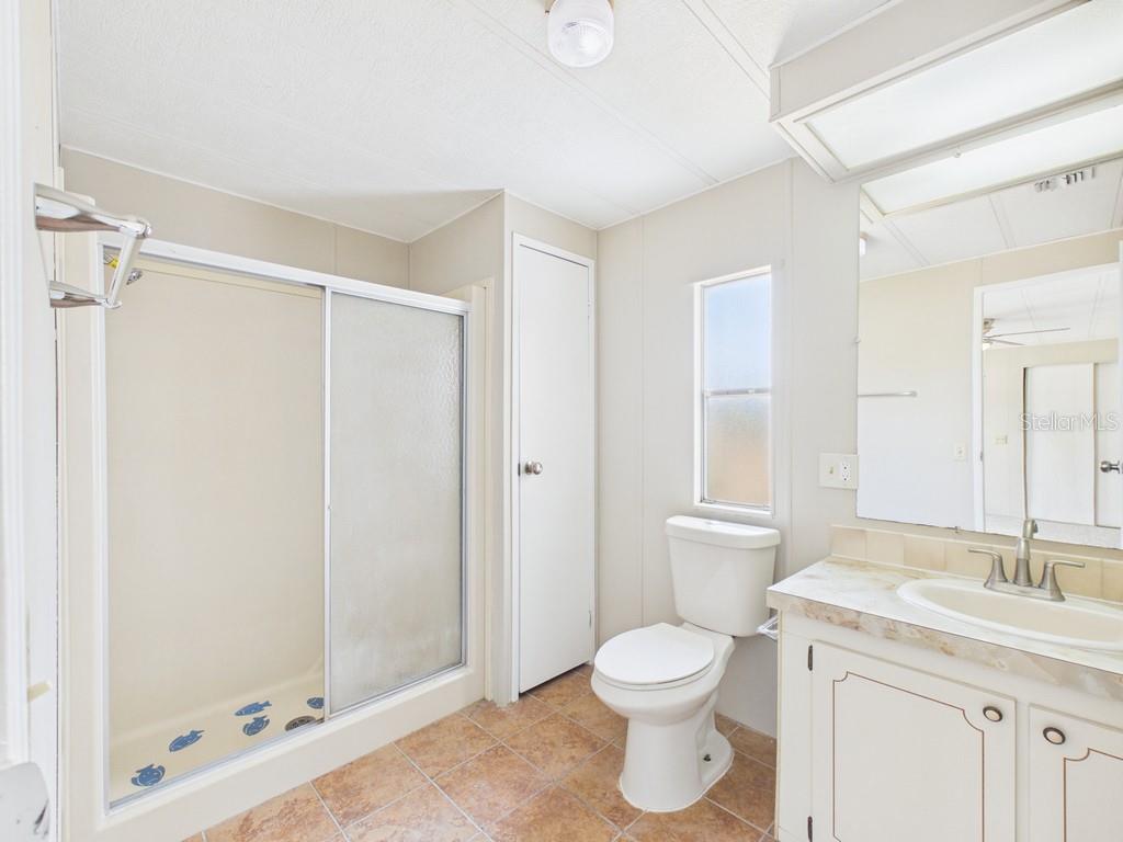 A bathroom features a walk-in shower, a toilet, and a vanity with a mirror — 9212 DENMARSH DRIVE, BROOKSVILLE, FL