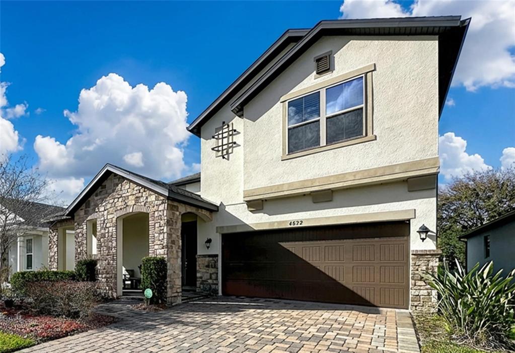 A two-story house with a stone facade, a paved driveway, and a two-car garage — 4892 ECHO COURT UNIT 44, OVIEDO, FL