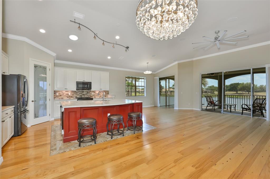 A kitchen with a red island, white cabinets, and hardwood floors opens to a patio — 1368 EMERALD DUNES DRIVE, SUN CITY CENTER, FL