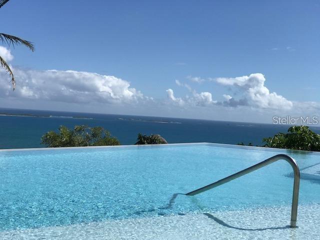 An infinity pool overlooks the ocean under a blue sky with scattered clouds — LAS CASITAS VILLAGE 1 AVE CONQUISTADOR UNIT 5391, FAJARDO, PR