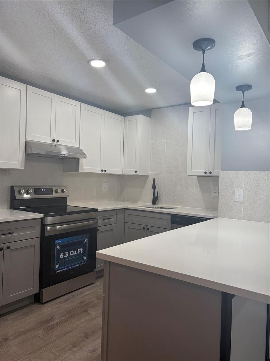 A kitchen features white upper cabinets, gray lower cabinets, stainless steel appliances, and white countertops — 5492 Courtyard Drive # 5492, Margate FL 33063, MARGATE, FL