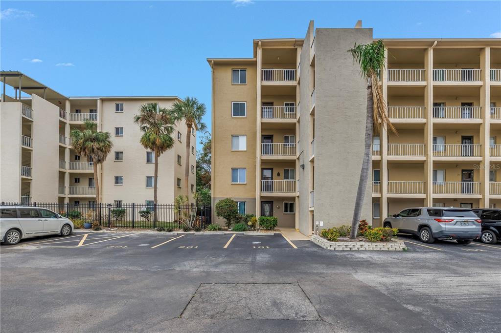 A multi-story apartment building with balconies and a parking lot in the foreground — 3500 LAKE BAYSHORE DRIVE UNIT K101, BRADENTON, FL