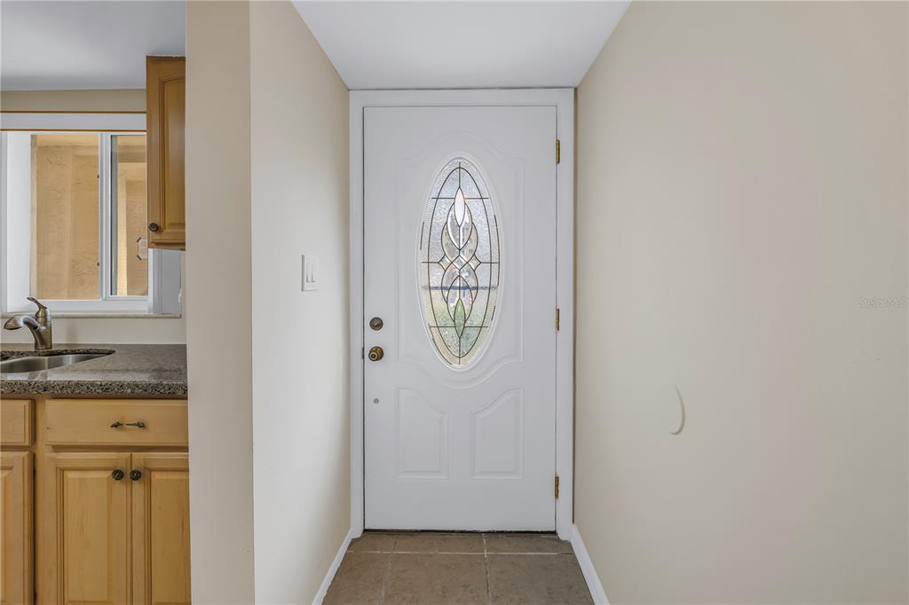 A white front door with an oval glass insert sits beside a kitchen counter area — 3500 LAKE BAYSHORE DRIVE UNIT K101, BRADENTON, FL