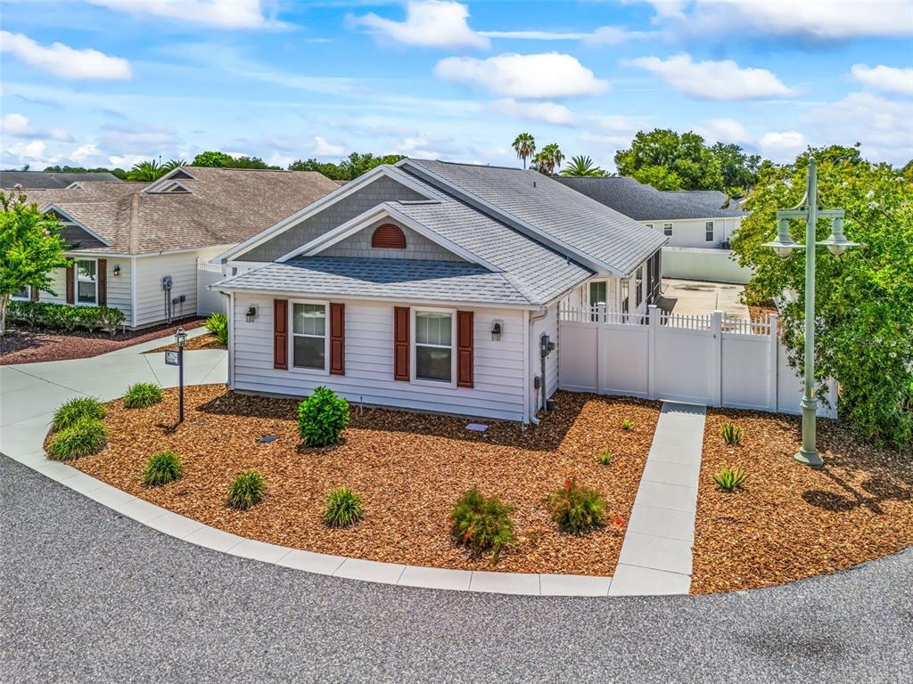 A single-story house with light siding, brown shutters, and a mulched front yard — 1134 SOUTHERN SUN DRIVE, THE VILLAGES, FL