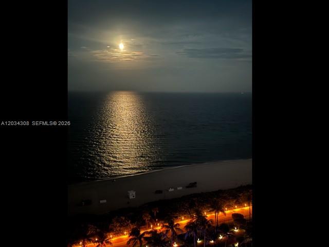An elevated night view of a moonlit ocean, sandy beach, and illuminated palm trees — 4779 Collins Ave # 1804, Miami Beach FL 33140, MIAMI BEACH, FL