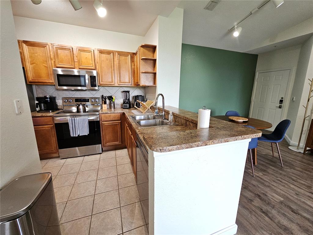 A kitchen features wood cabinets, stainless steel appliances, and a breakfast bar with laminate countertops — 8335 38TH STREET CIRCLE E UNIT 305, SARASOTA, FL