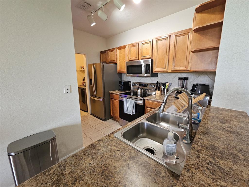 A kitchen features wood cabinets, stainless steel appliances, a double sink, and granite countertops — 8335 38TH STREET CIRCLE E UNIT 305, SARASOTA, FL