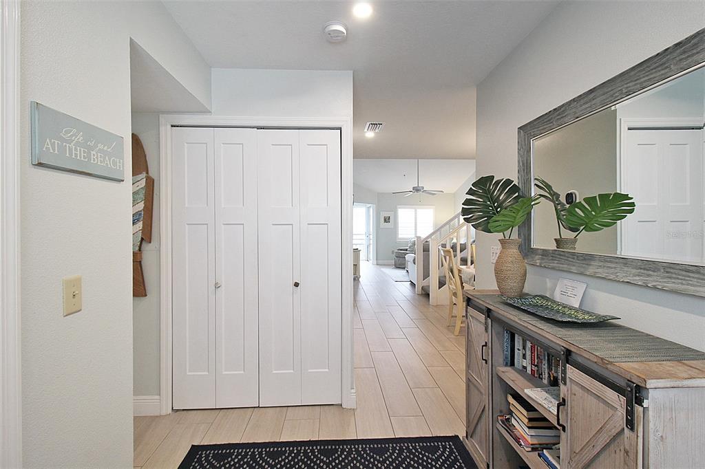 A hallway features light tile flooring, a white closet, and a rustic console table with decor — 1275 SIESTA BAYSIDE DRIVE UNIT 1275-B, SARASOTA, FL