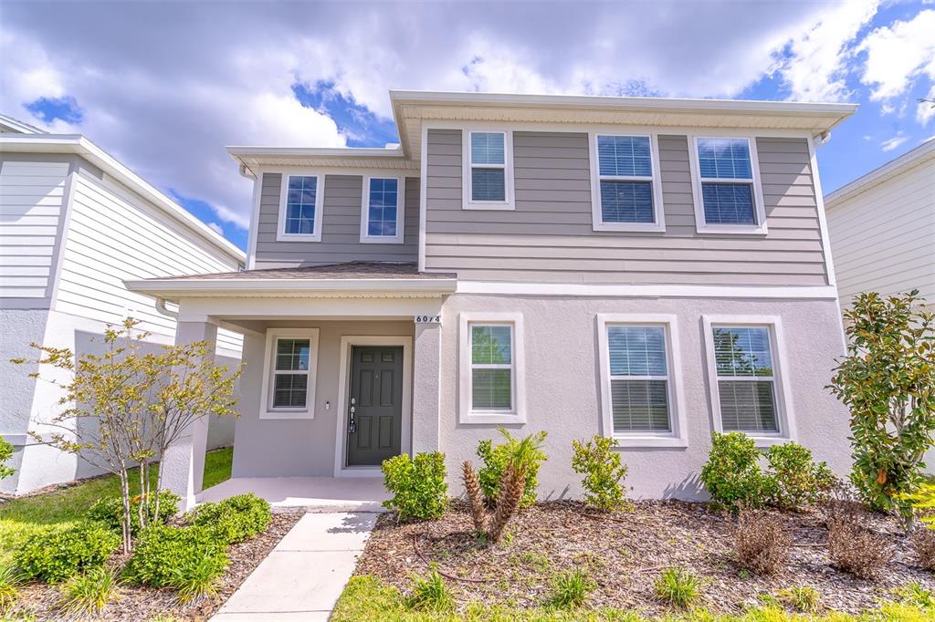 A two-story house with gray siding, a stucco lower level, and a covered front porch — 6074 WINDY LEAF ALLEY, ST CLOUD, FL