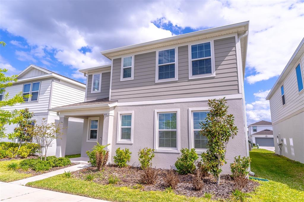 A two-story house with gray horizontal siding and light-colored stucco exterior walls — 6074 WINDY LEAF ALLEY, ST CLOUD, FL