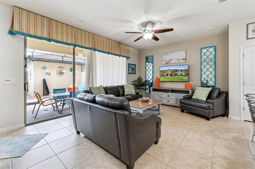 A living room with dark leather furniture, a television, and a sliding door to a patio — 1909 MAJORCA DRIVE, KISSIMMEE, FL