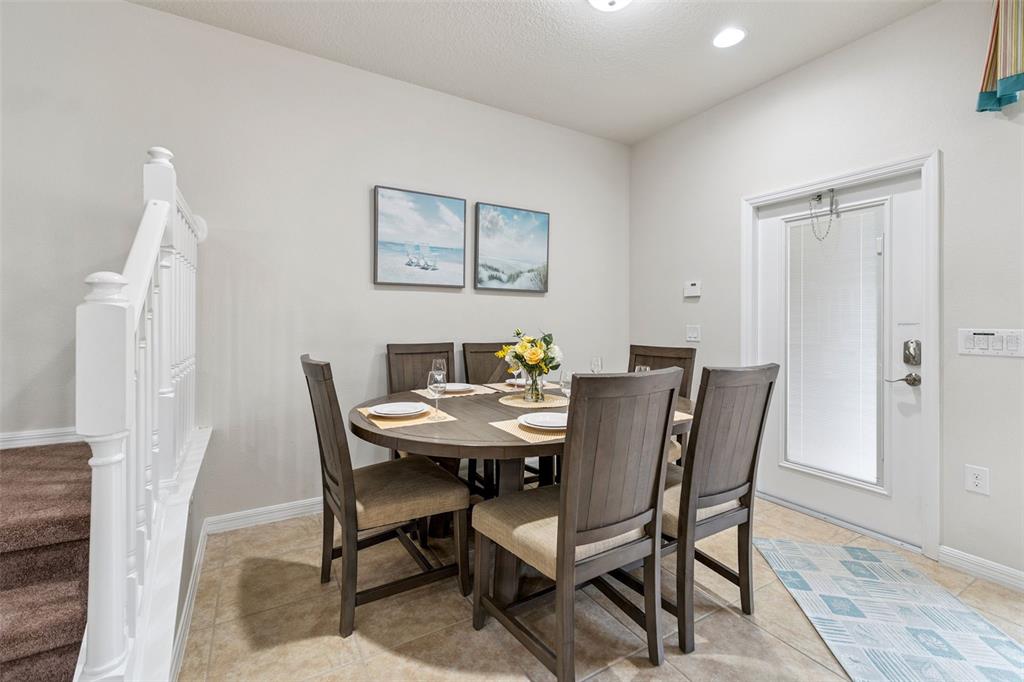 A dining area features a round wooden table with six chairs and two beach-themed wall prints — 1909 MAJORCA DRIVE, KISSIMMEE, FL