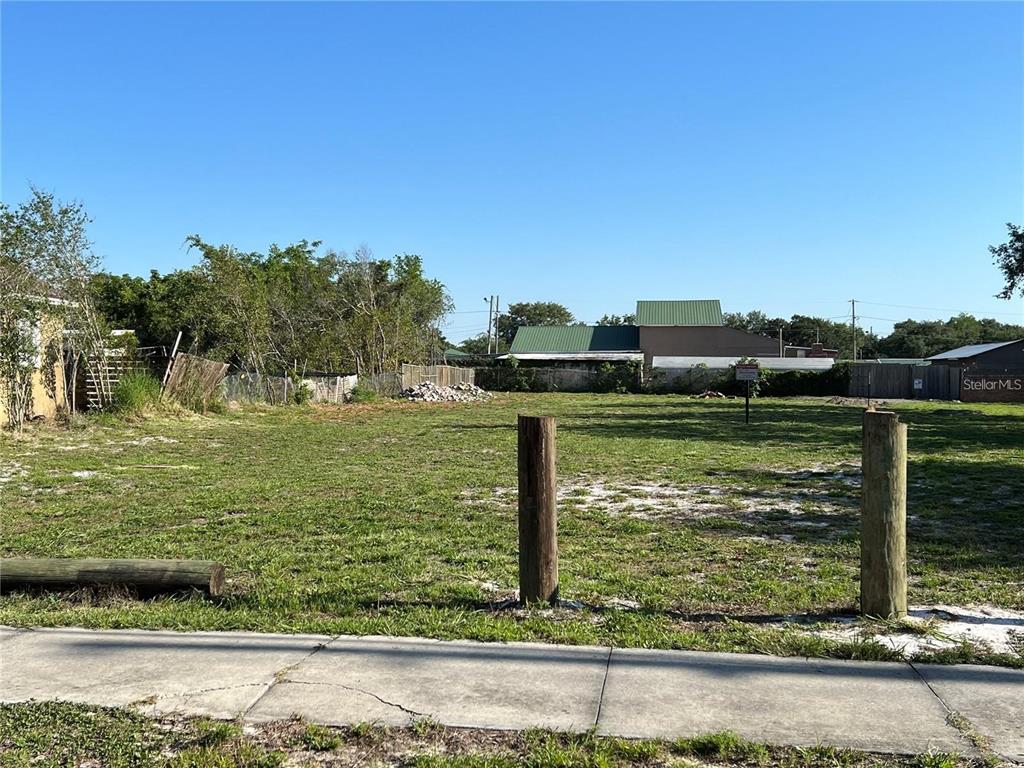 A vacant, grassy lot features two wooden posts in the foreground and a sidewalk — O E NANCY LEE LANE, APOPKA, FL