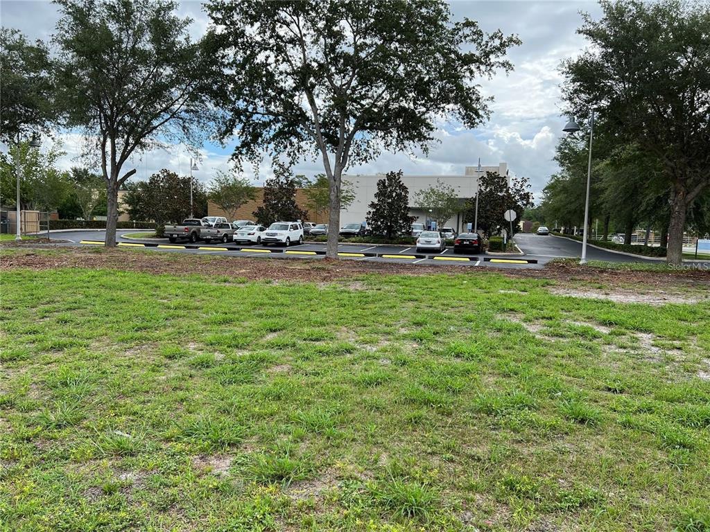 A grassy lot sits in front of a parking area with cars and a commercial building — O E NANCY LEE LANE, APOPKA, FL