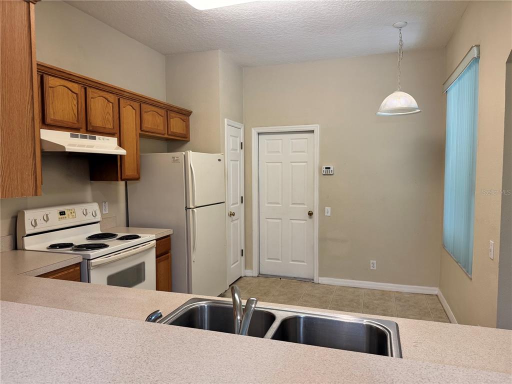 A kitchen features wood cabinets, white appliances, a double sink, and a tiled floor — 4107 KEY THATCH DRIVE, TAMPA, FL