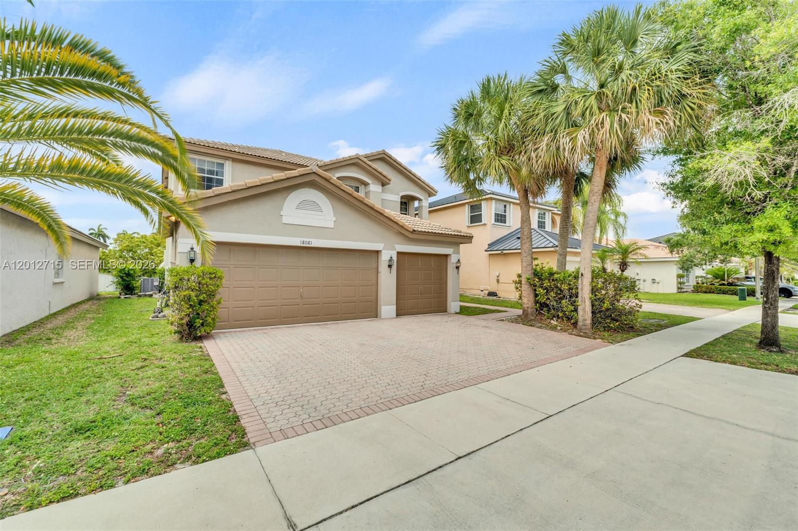 A two-story suburban house features a tan stucco exterior, a paved driveway, and palm trees — 18081 SW 33rd St, Miramar FL 33029, MIRAMAR, FL