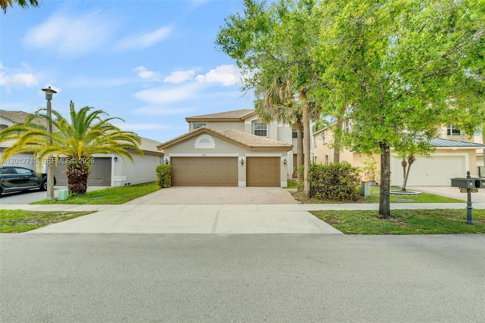 A two-story suburban house with a tan stucco exterior, tile roof, and three-car garage — 18081 SW 33rd St, Miramar FL 33029, MIRAMAR, FL