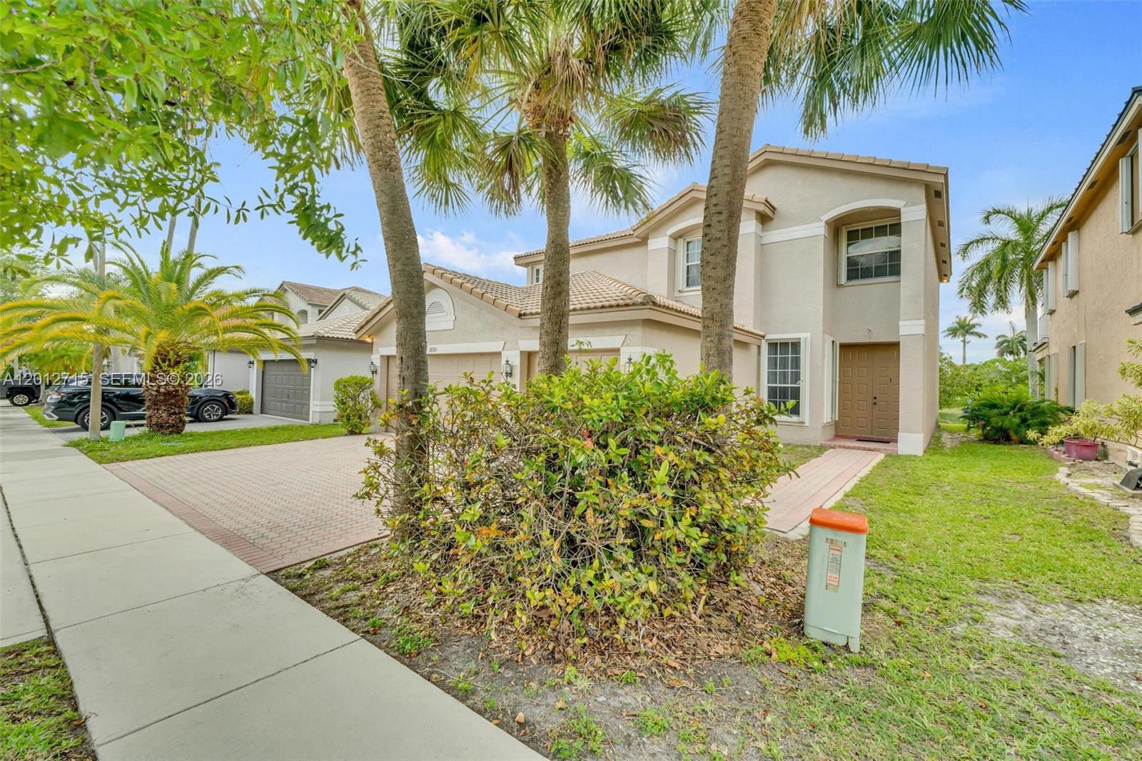 A two-story suburban house with a paved driveway, palm trees, and a tan stucco exterior — 18081 SW 33rd St, Miramar FL 33029, MIRAMAR, FL
