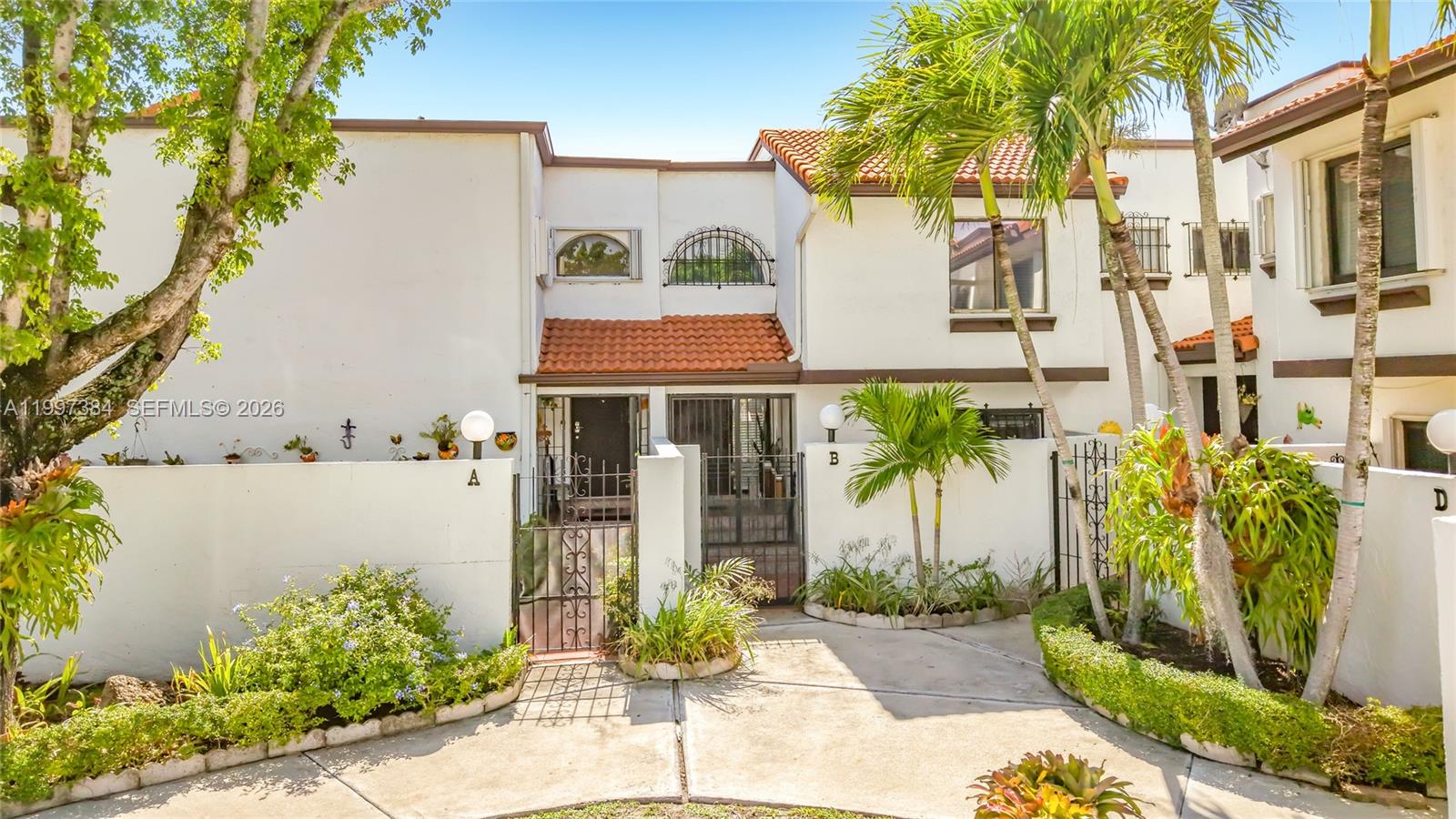 The exterior view shows two adjacent townhome units with white walls, tiled roofs, and courtyards — 1291 SW 124th Ct # B, Miami FL 33184, MIAMI, FL